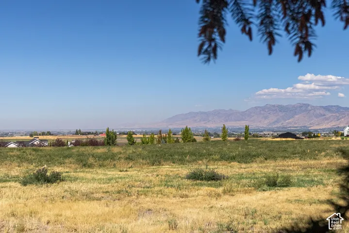 Expansive rural landscape with distant mountain ranges and scattered residential structures