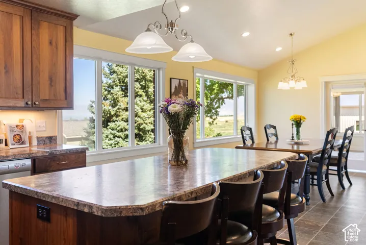 Kitchen featuring wood cabinetry, an extended island with a stone-finish countertop, and recessed lighting