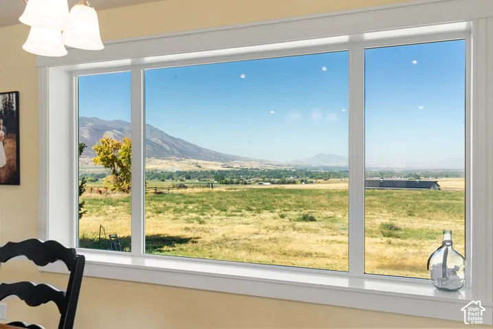 Expansive multi-pane window with white trim, showcasing distant mountains and a broad rural landscape