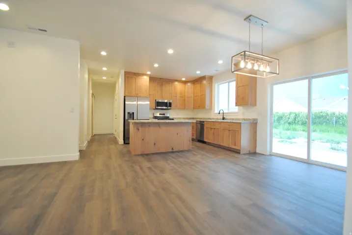 Open-concept kitchen featuring wood cabinetry, stainless steel appliances, a kitchen island, and recessed lighting