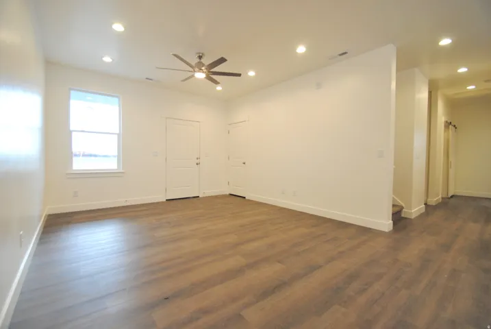 Spacious living area featuring wood-finish flooring, recessed lighting, a ceiling fan, and white trim