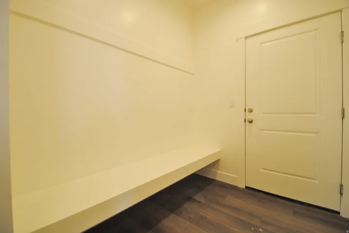 Built-in bench seating with a coat rack, two-panel interior door, and wood-finish flooring