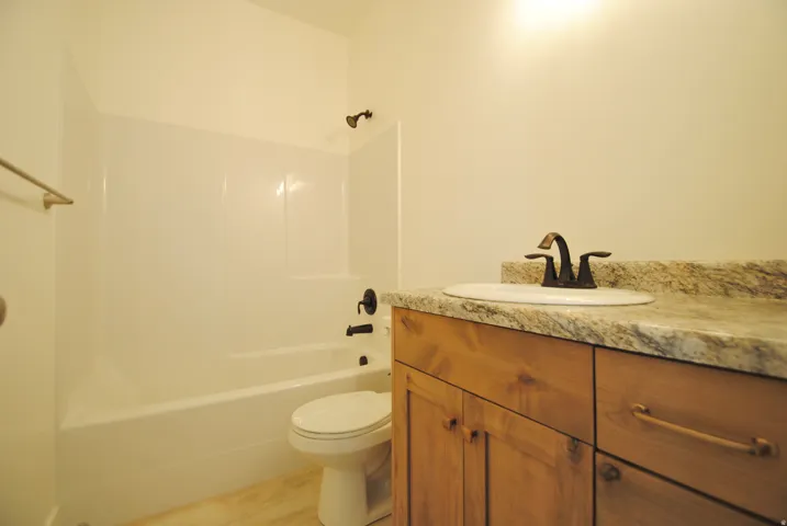 Wood-finish vanity with an integrated sink and countertop.   The mirror has also been installed since the photo.