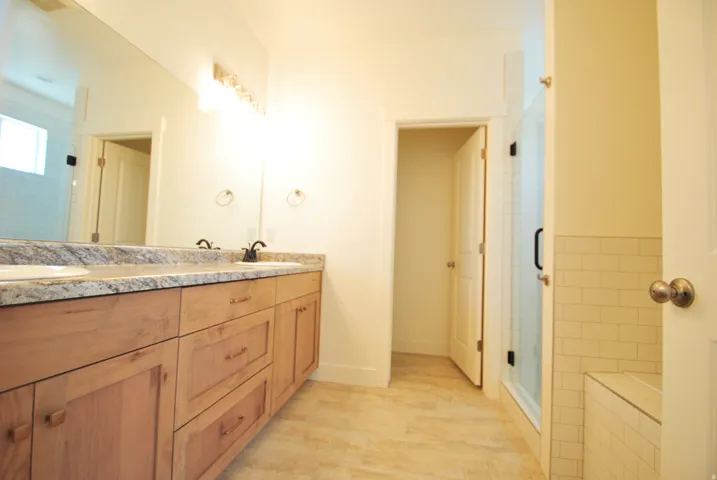 Dual vanity with integrated sinks, speckled countertop, and wood-finish cabinetry