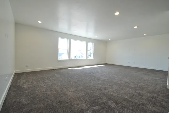 Family room featuring neutral carpeting, recessed lighting, and multiple windows