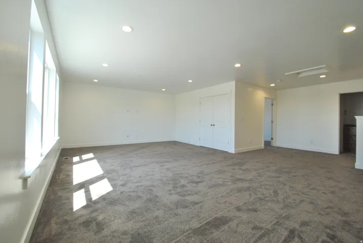 Family room with recessed ceiling lighting, white walls, gray textured carpeting, white trim, and a white double door closet