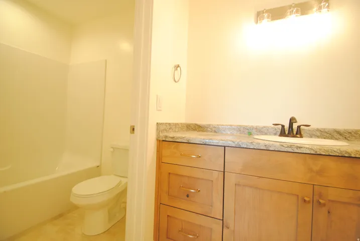 Wood-finish vanity with an integrated sink and bronze-finish faucet, the mirror has also been installed since the photo.