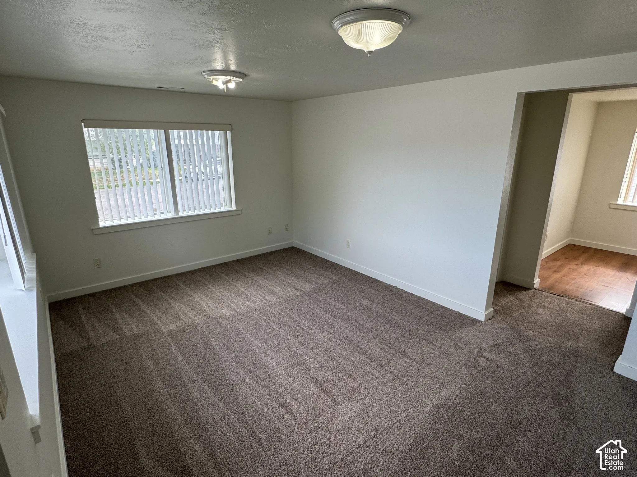 Recessed window with vertical blinds, textured ceiling, and built-in ceiling lighting
