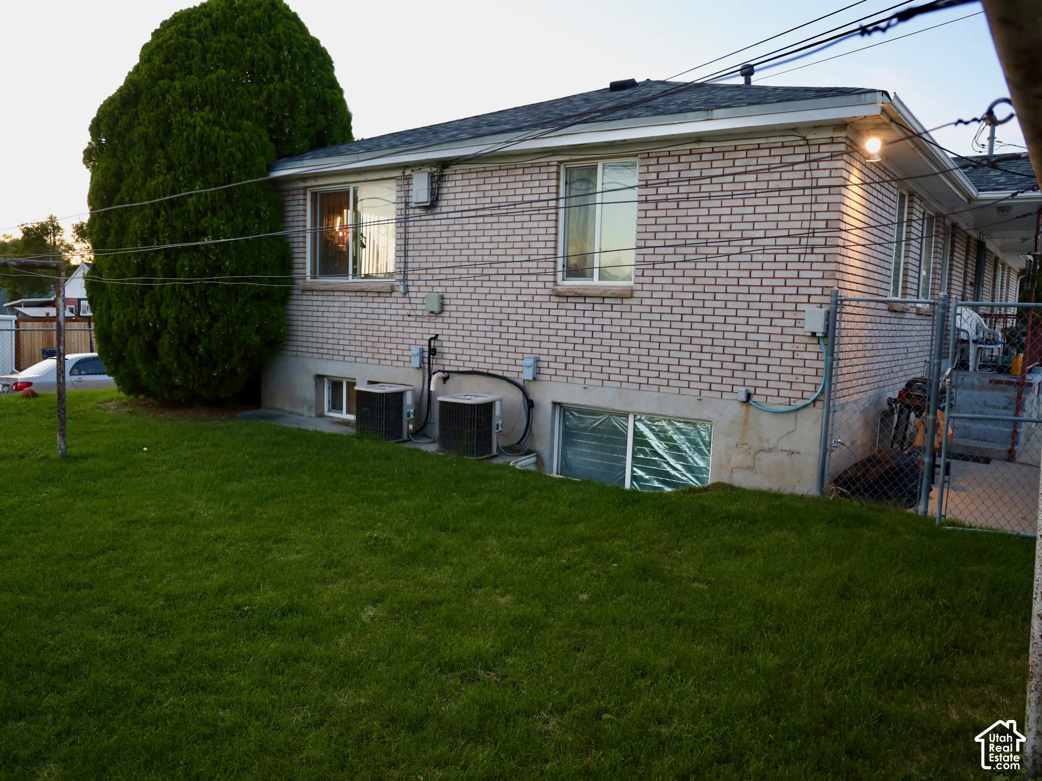 Brick exterior with multiple windows, a mature tree, and a grassy area