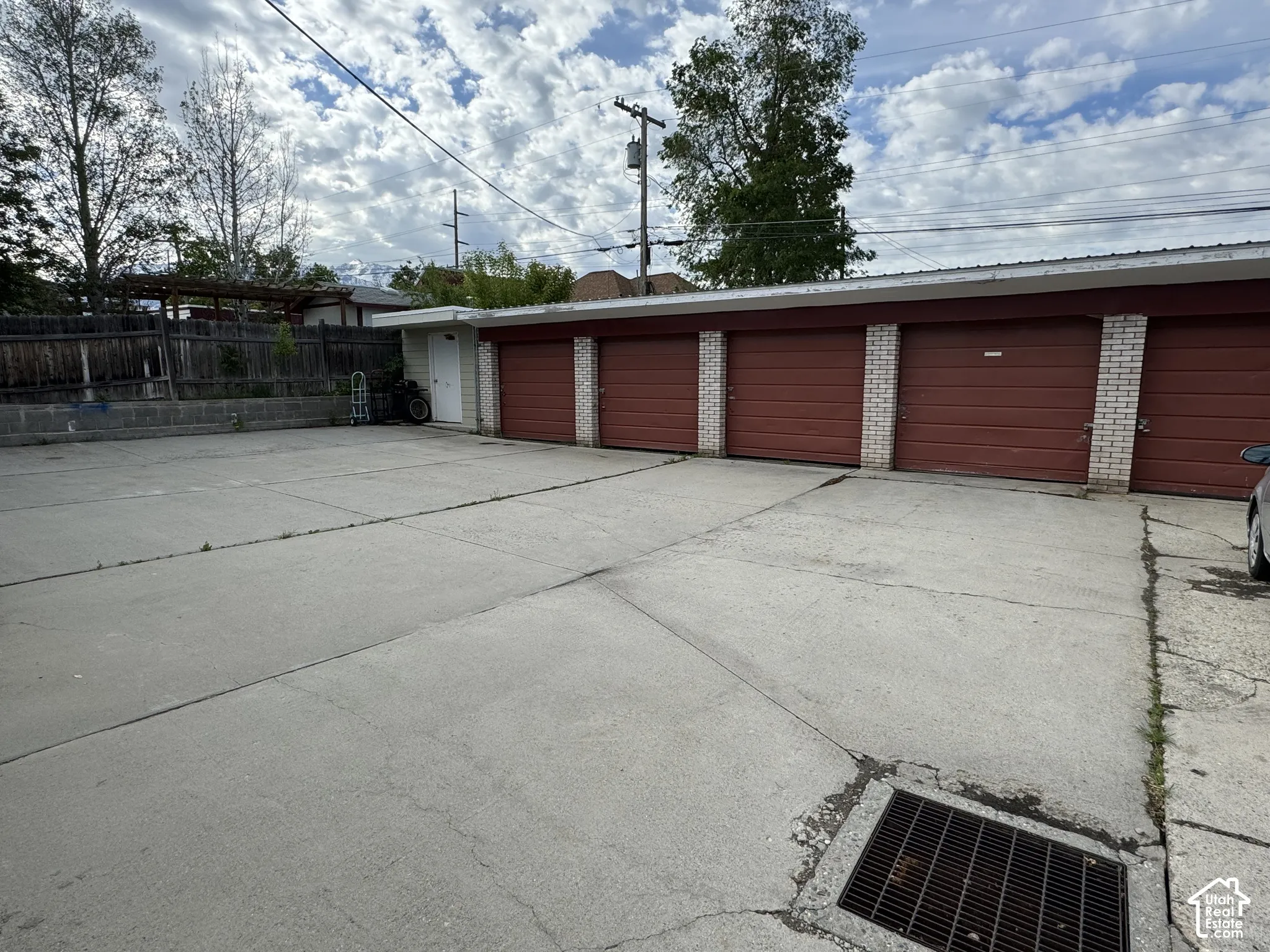 Multi-unit garage structure featuring four individual doors, brick pillars, a metal roof, and an adjacent exterior access door