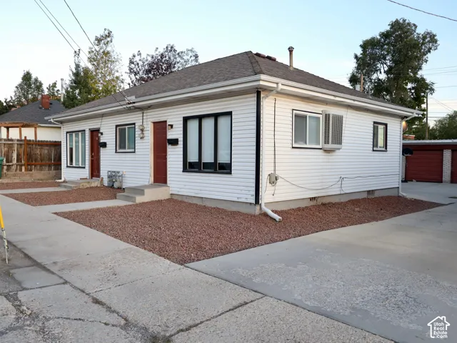 White siding exterior with dark trim windows, dual entry doors, gabled roof, and gravel landscaping