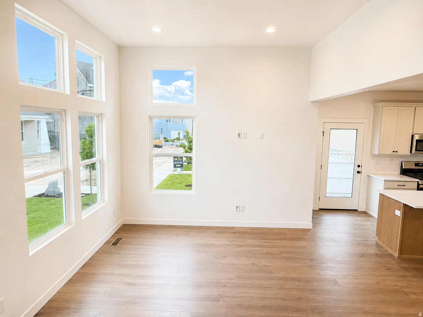 Wood-finish flooring, high ceilings, recessed lighting, multiple windows, and a glass-paneled door