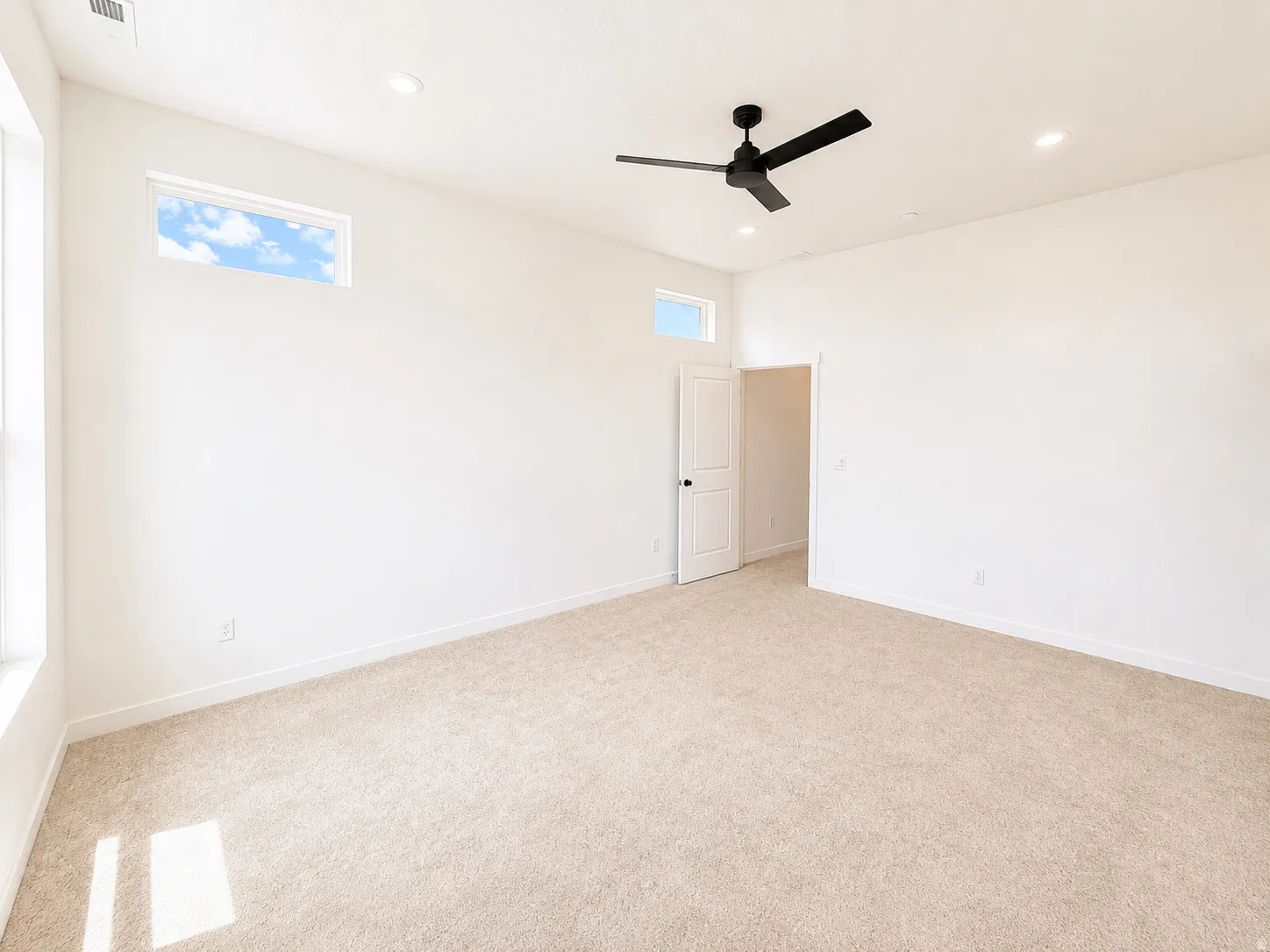 Recessed lighting, large windows, high ceilings, ceiling fan, and light-toned carpeting