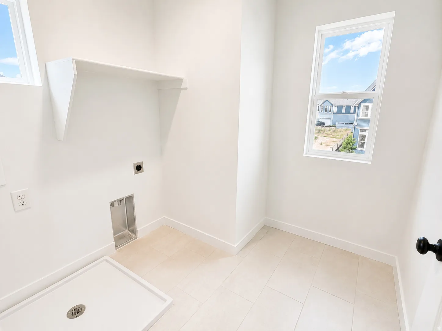 Laundry area featuring a built-in shelf, two windows, tiled flooring, and a utility sink base