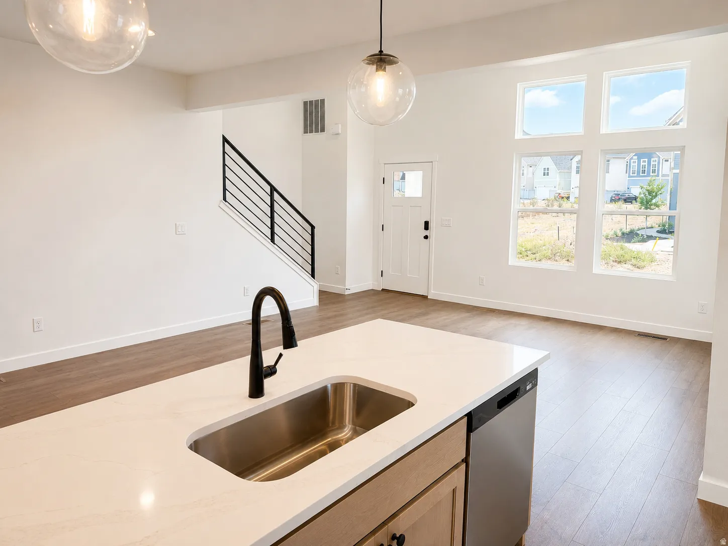Kitchen island with an undermount stainless steel sink, matte black faucet, and light-toned countertop
