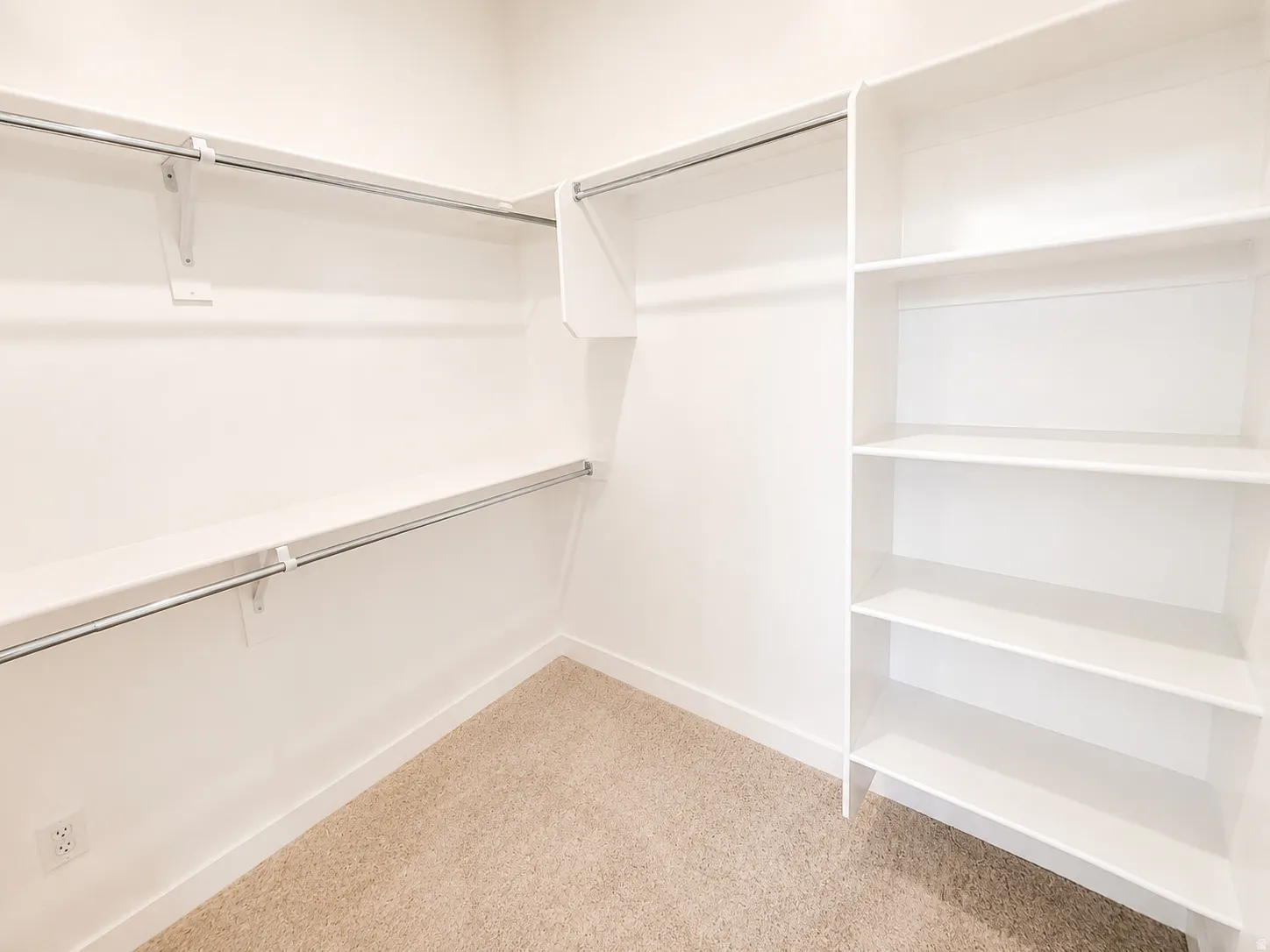 Built-in shelving, chrome hanging rods, and neutral carpeting