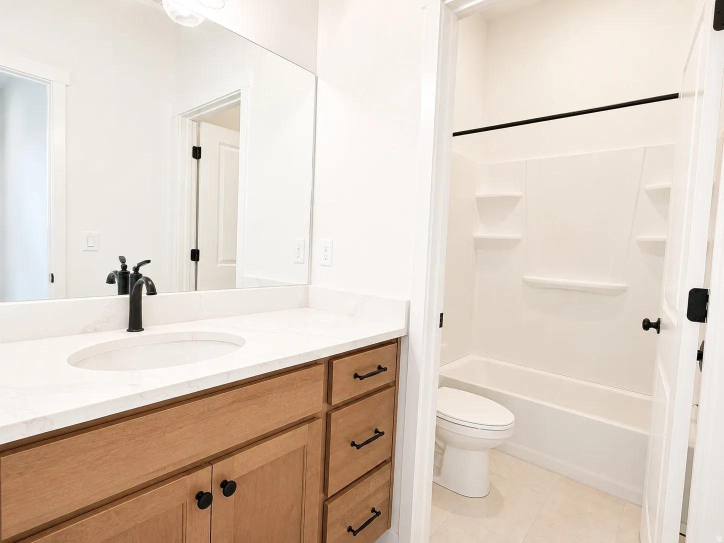 Bathroom featuring a single vanity with wood-finish cabinetry, a white countertop, and a matte black faucet