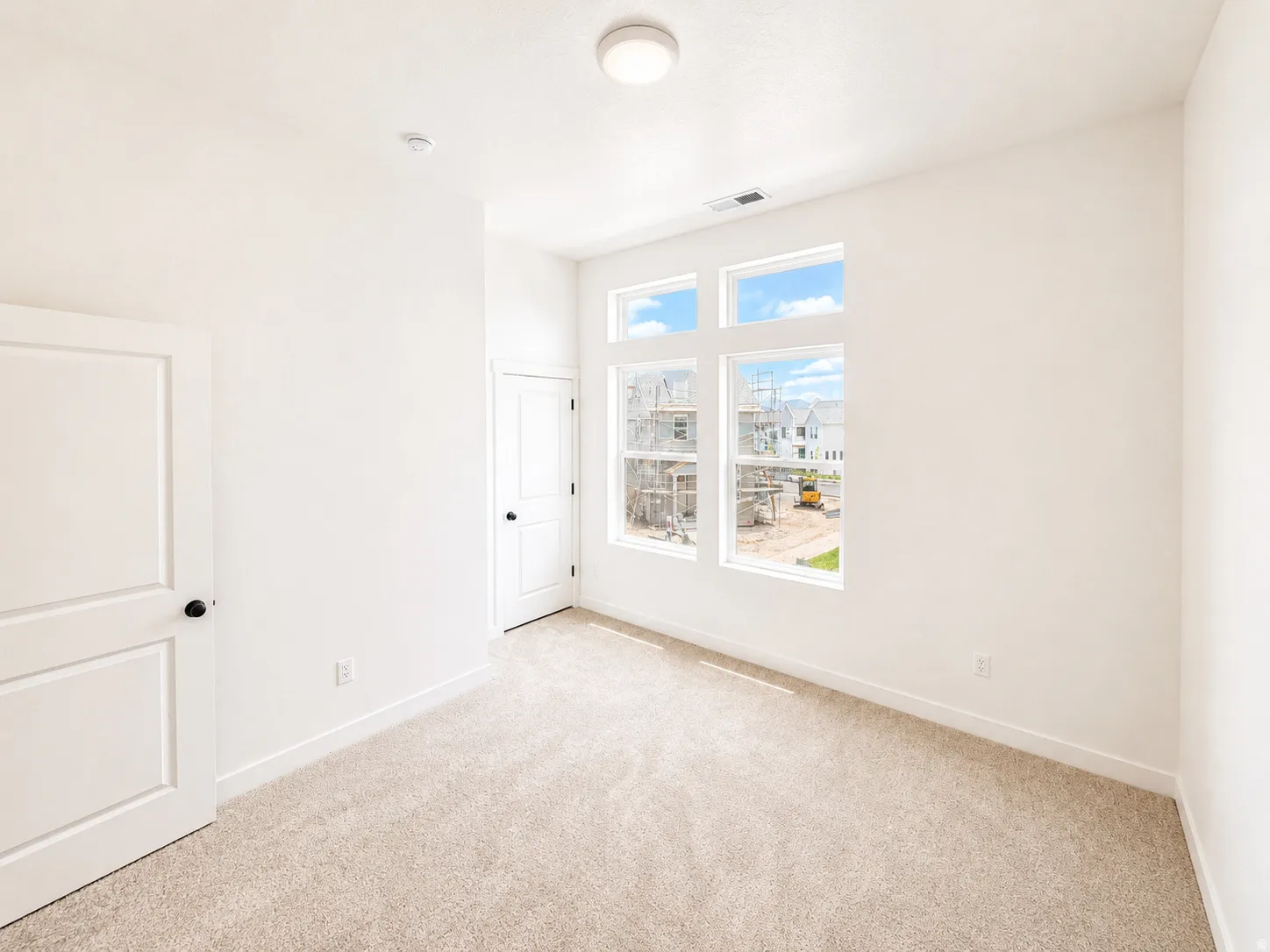 Bright interior space featuring light-toned carpet, white walls, and a contemporary flush-mount ceiling light