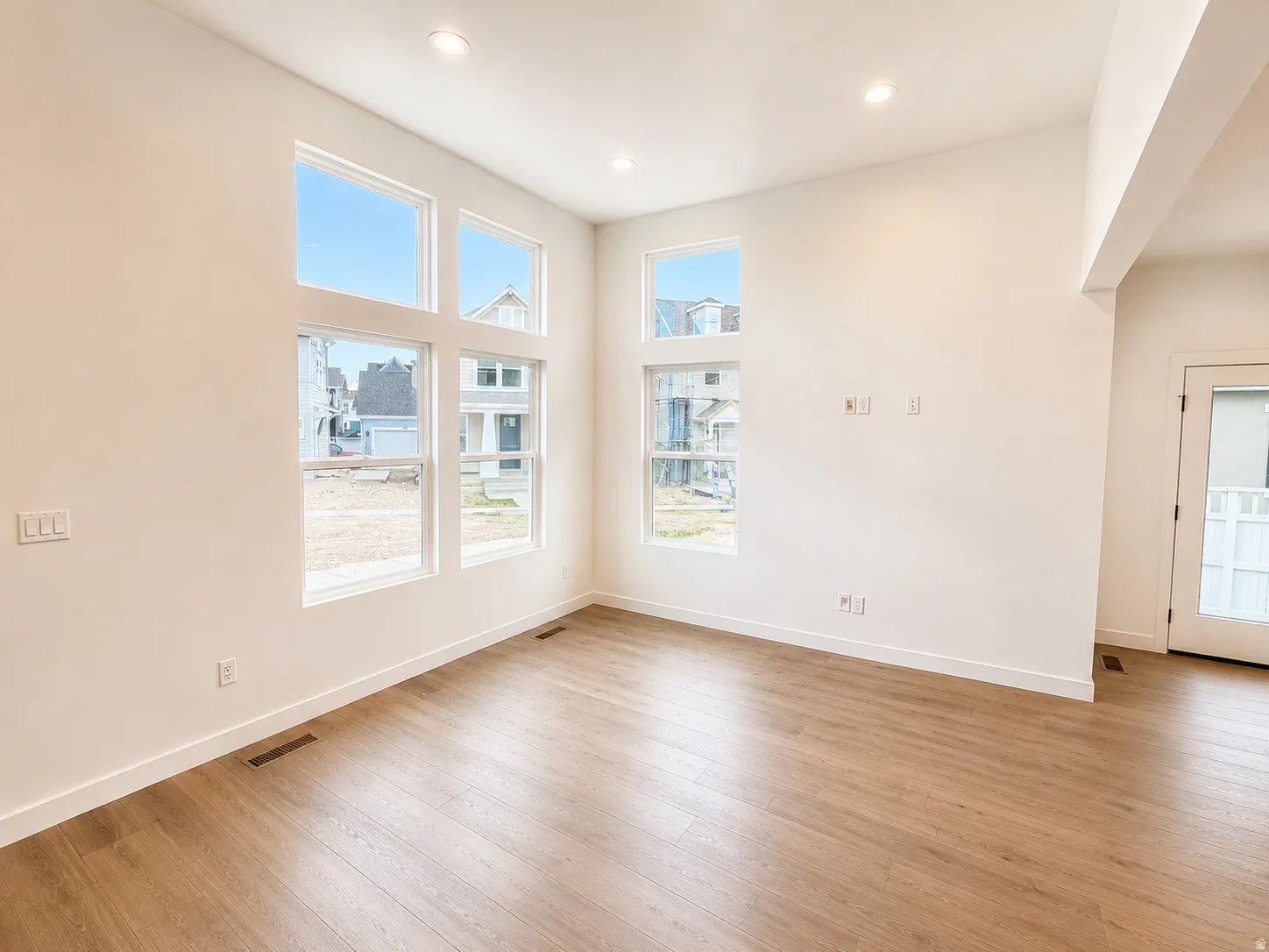 High ceilings, recessed lighting, expansive windows, wood-finish flooring, and a glass-paneled exterior door