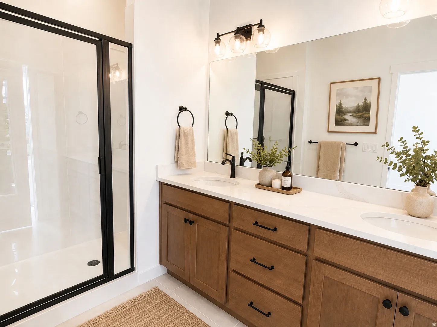 Dual vanity with white countertops, wood-finish cabinetry, matte black hardware, and an adjacent walk-in shower with a black-framed glass enclosure