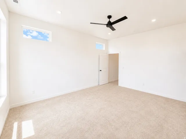 Recessed lighting, large windows, high ceilings, ceiling fan, and light-toned carpeting