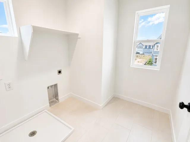 Laundry area featuring a built-in shelf, two windows, tiled flooring, and a utility sink base