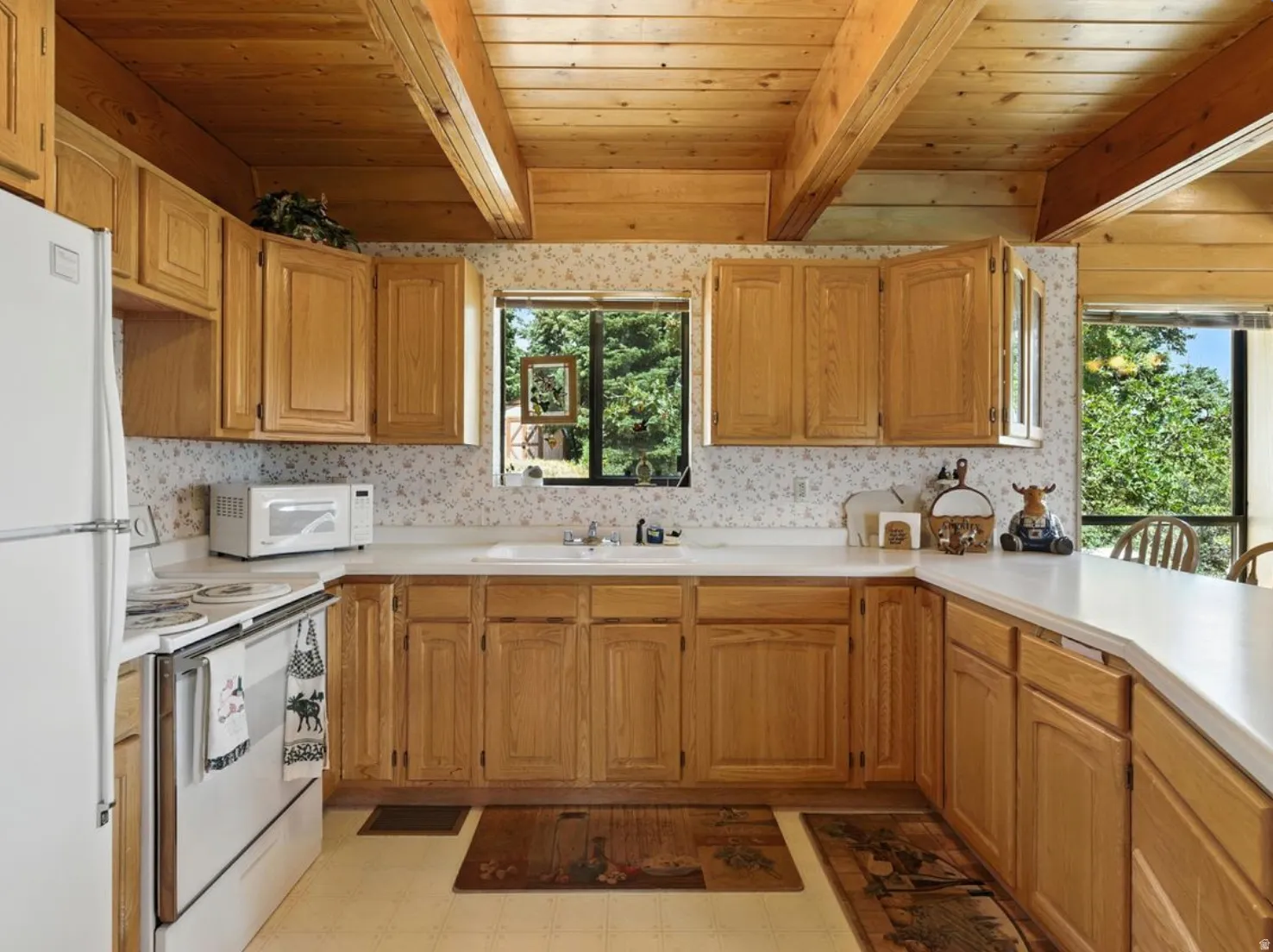 Kitchen featuring wood cabinetry, white countertops, built-in sink, and wood-paneled ceiling with exposed beams