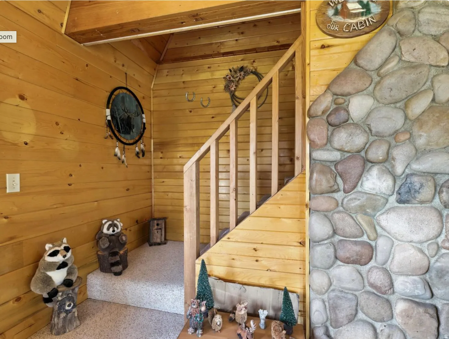 Natural wood-paneled walls, exposed wood ceiling beams, wood staircase with railing, and a stone-clad wall accent