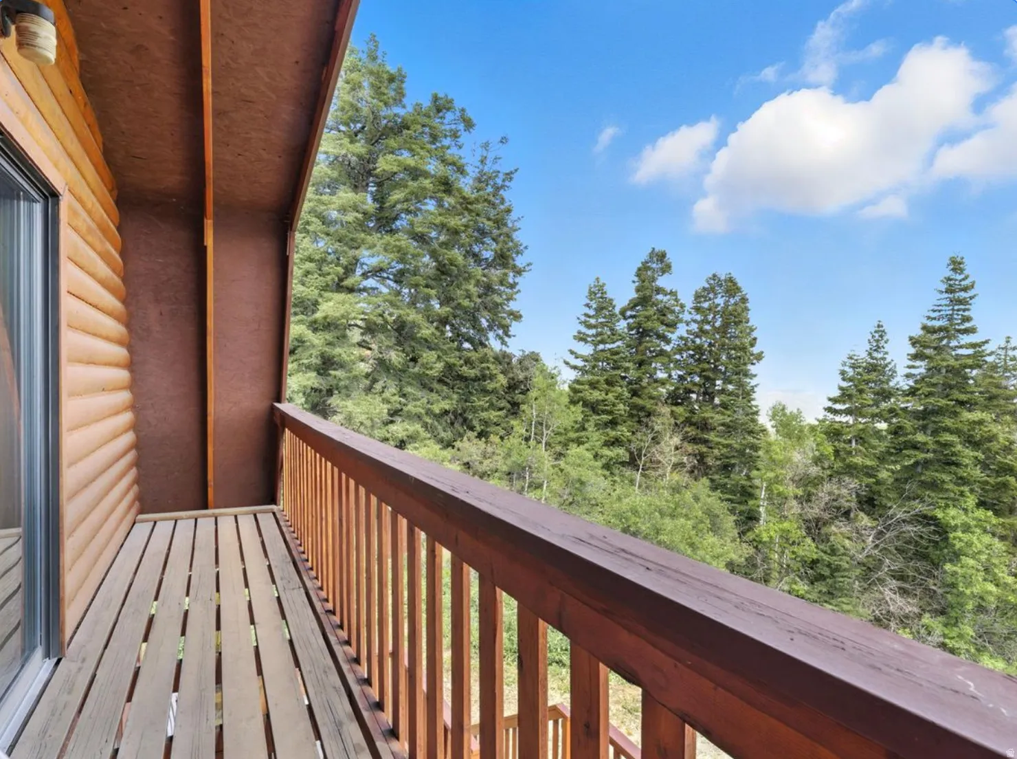 Wood-sided exterior with an attached balcony featuring slat flooring and a wood railing