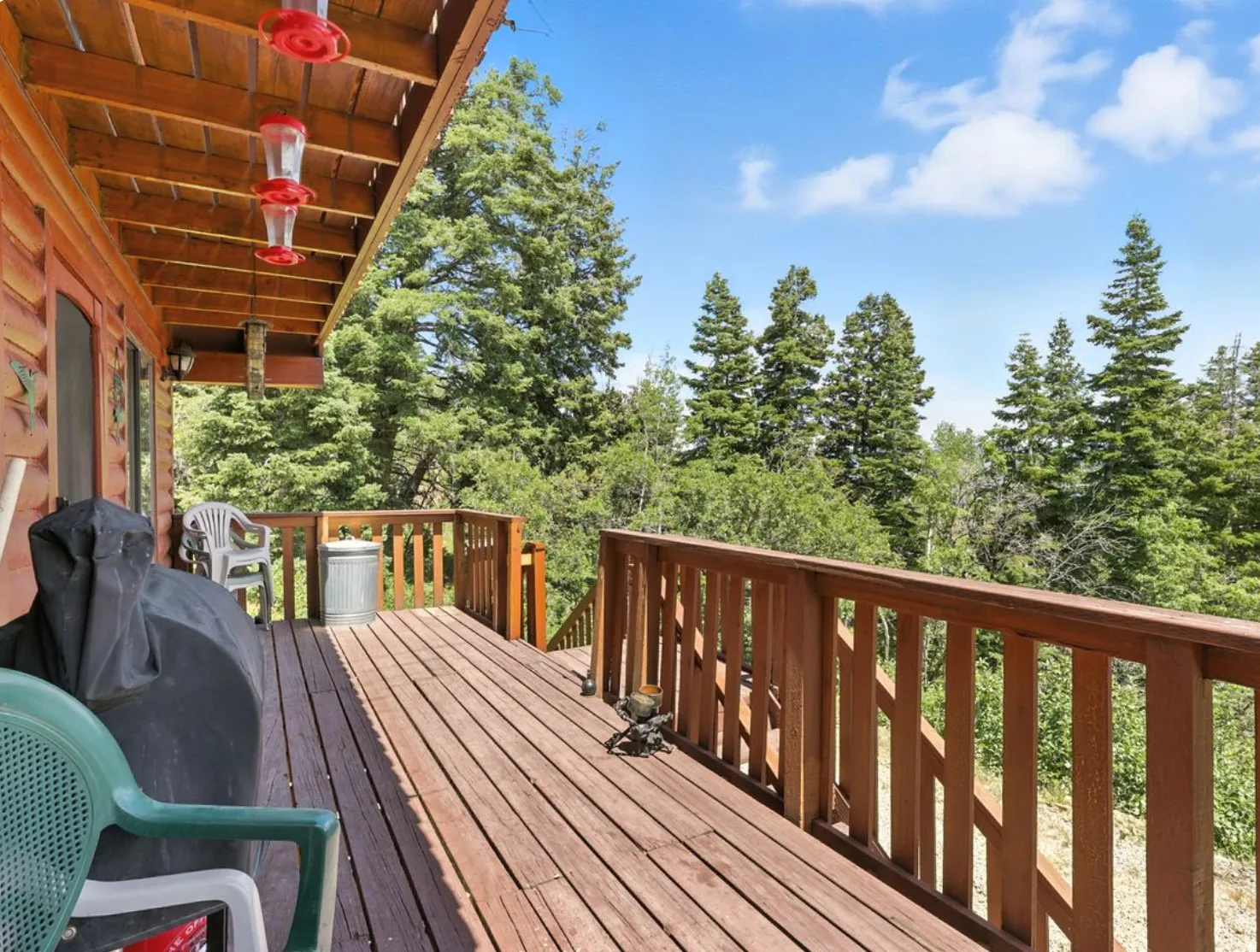 Expansive outdoor deck with wood-finish railing, wood-finish flooring, and a natural tree-lined backdrop