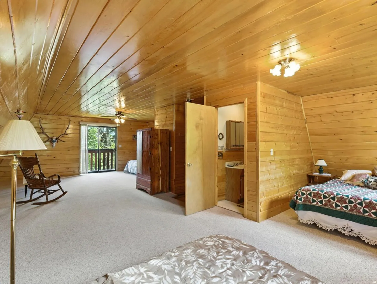 Wood-paneled walls and ceiling, carpeted flooring, built-in ceiling lighting, and a sliding glass door with balcony access