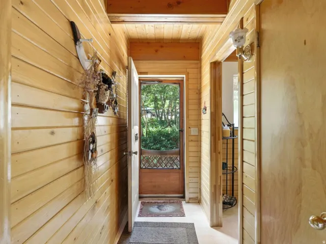 Wood-paneled hallway featuring a wood-finish ceiling, transom window, and a wall-mounted light fixture