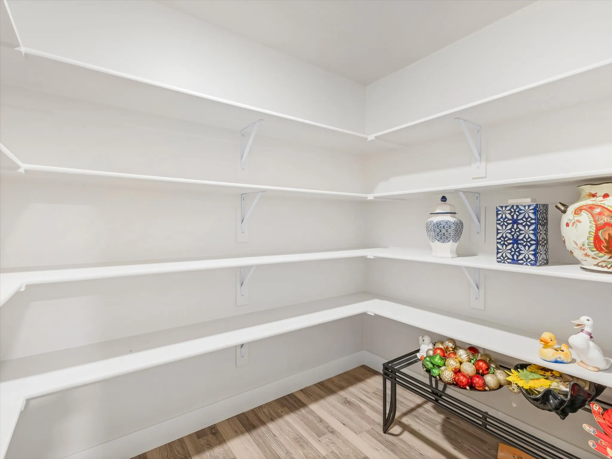 Corner pantry with multiple white wire shelves and wood-finish flooring