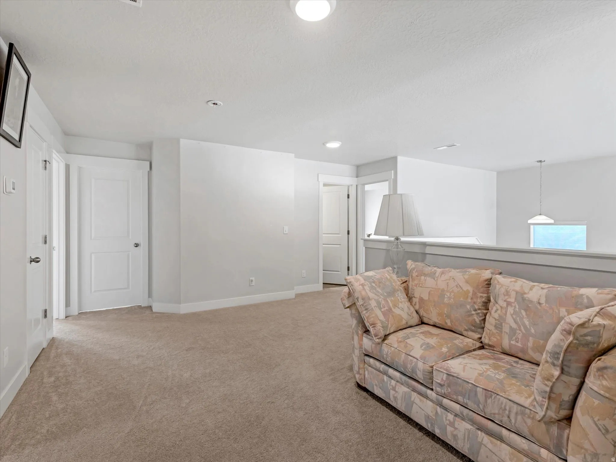 Carpeted flooring extending throughout, flush-mounted ceiling lights, and white painted walls