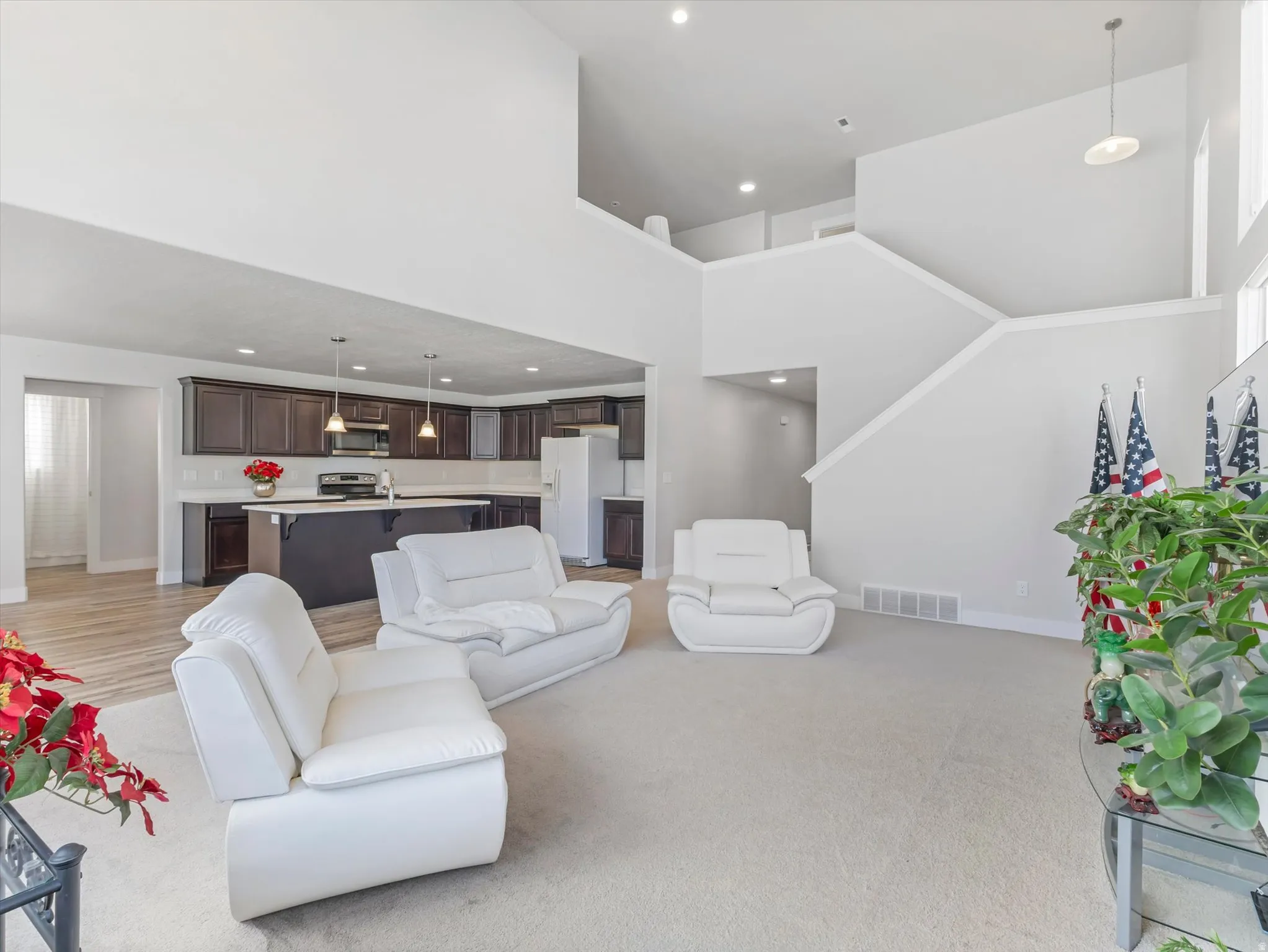 Two-story living area with high ceilings, an open staircase, and light-toned carpeting