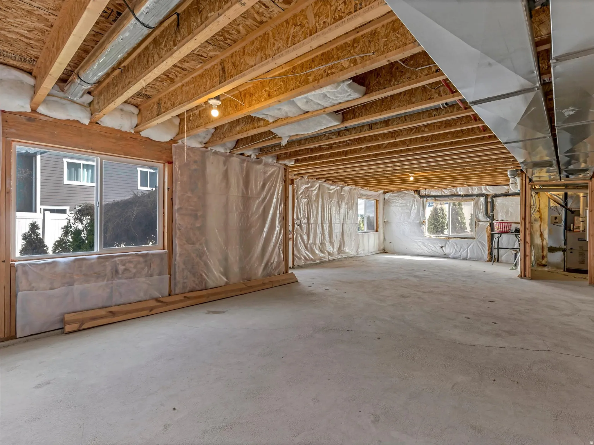 Unfinished lower level featuring exposed wood joists, concrete flooring, and multiple windows