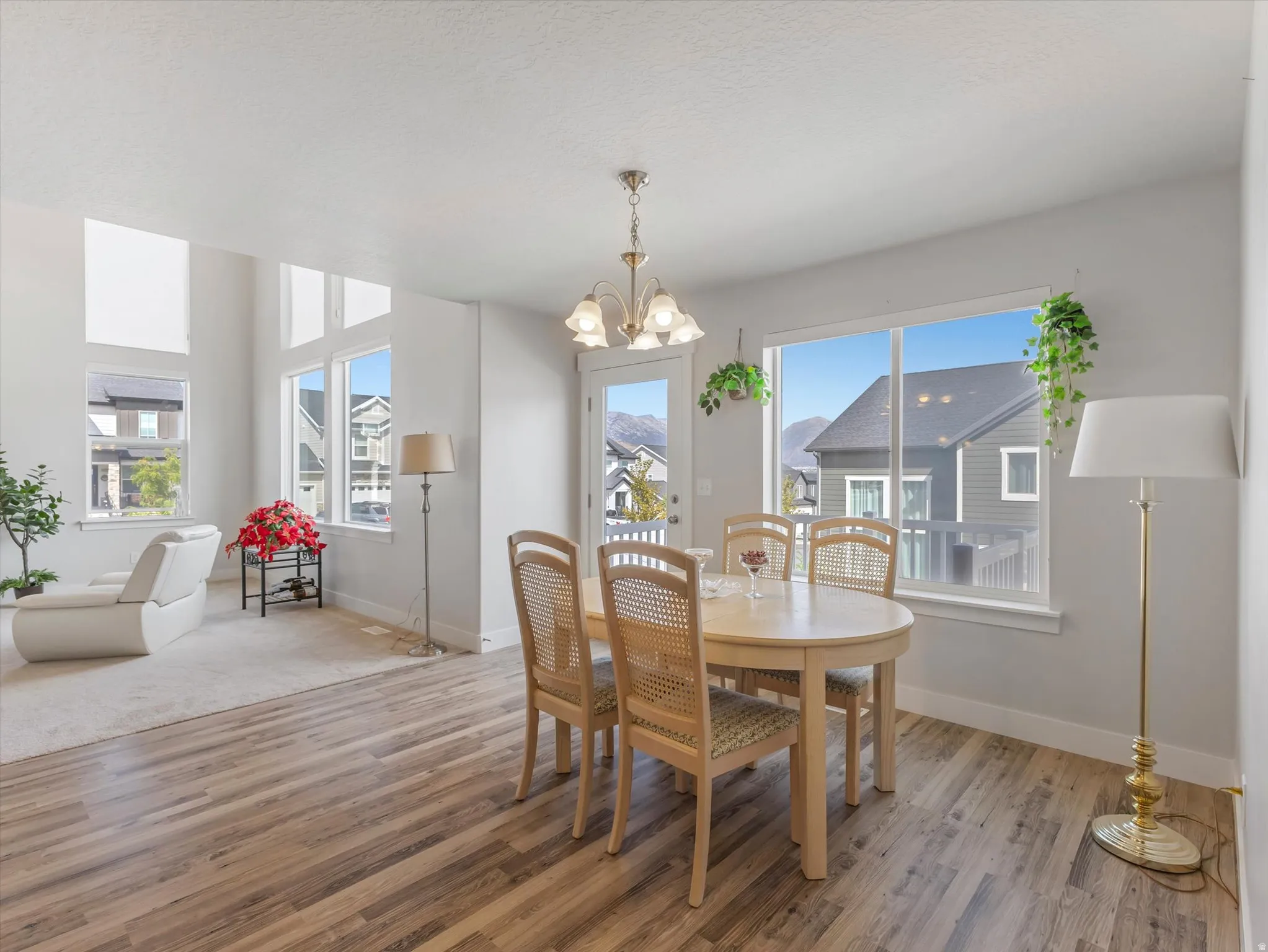 Expansive windows with transom accents, wood-finish flooring, recessed lighting, and a chandelier