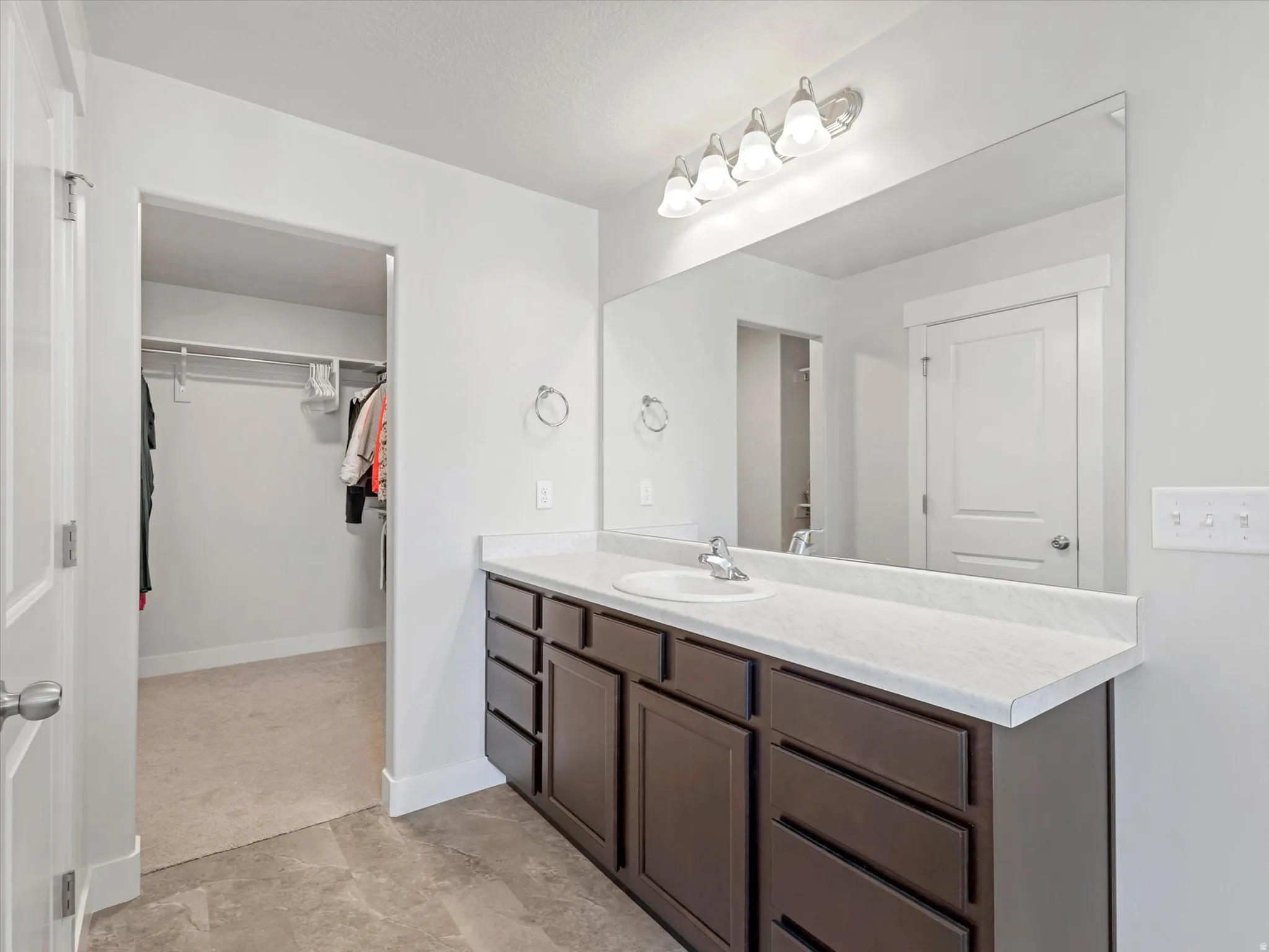 Bathroom vanity with a white countertop, undermount sink, and wood-finish cabinetry