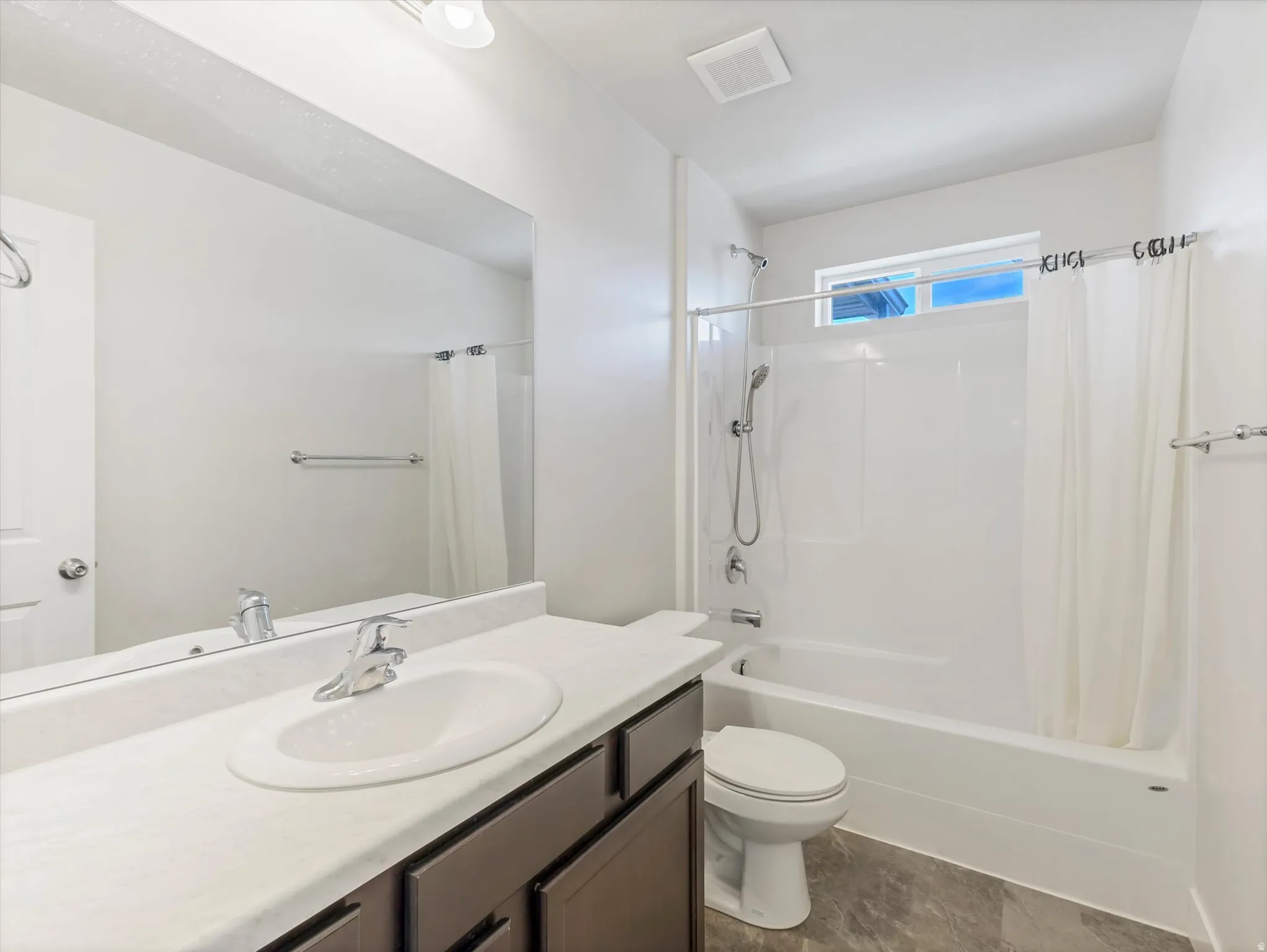 Bathroom featuring a single vanity, wood-finish cabinetry, a full-width mirror, a tub-shower combination, and tile flooring