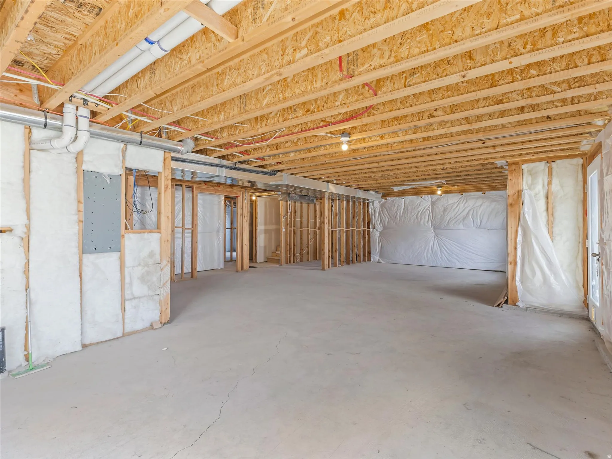 Unfinished lower level with exposed ceiling joists, concrete flooring, and framed interior walls