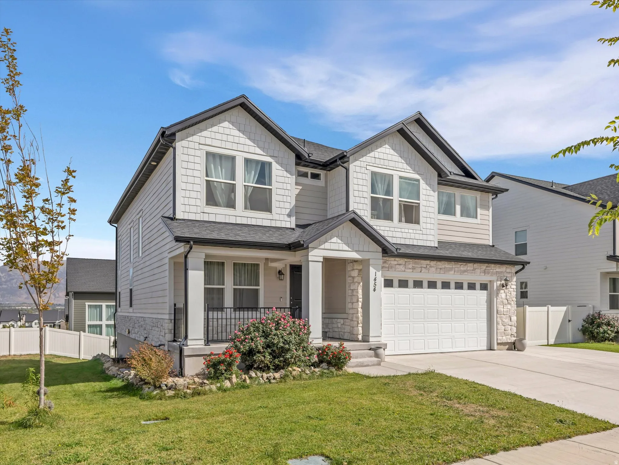Two-story residence featuring a covered entry, stone veneer accents, and a two-car garage