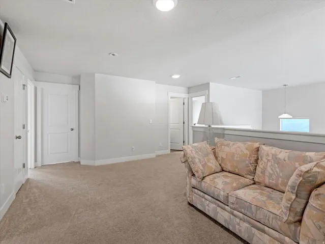 Carpeted flooring extending throughout, flush-mounted ceiling lights, and white painted walls