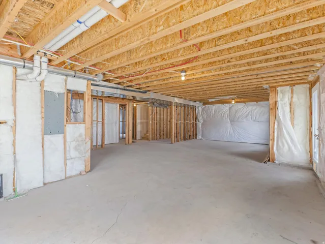 Unfinished lower level with exposed ceiling joists, concrete flooring, and framed interior walls