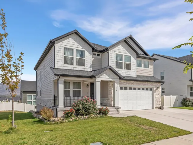Two-story residence featuring a covered entry, stone veneer accents, and a two-car garage