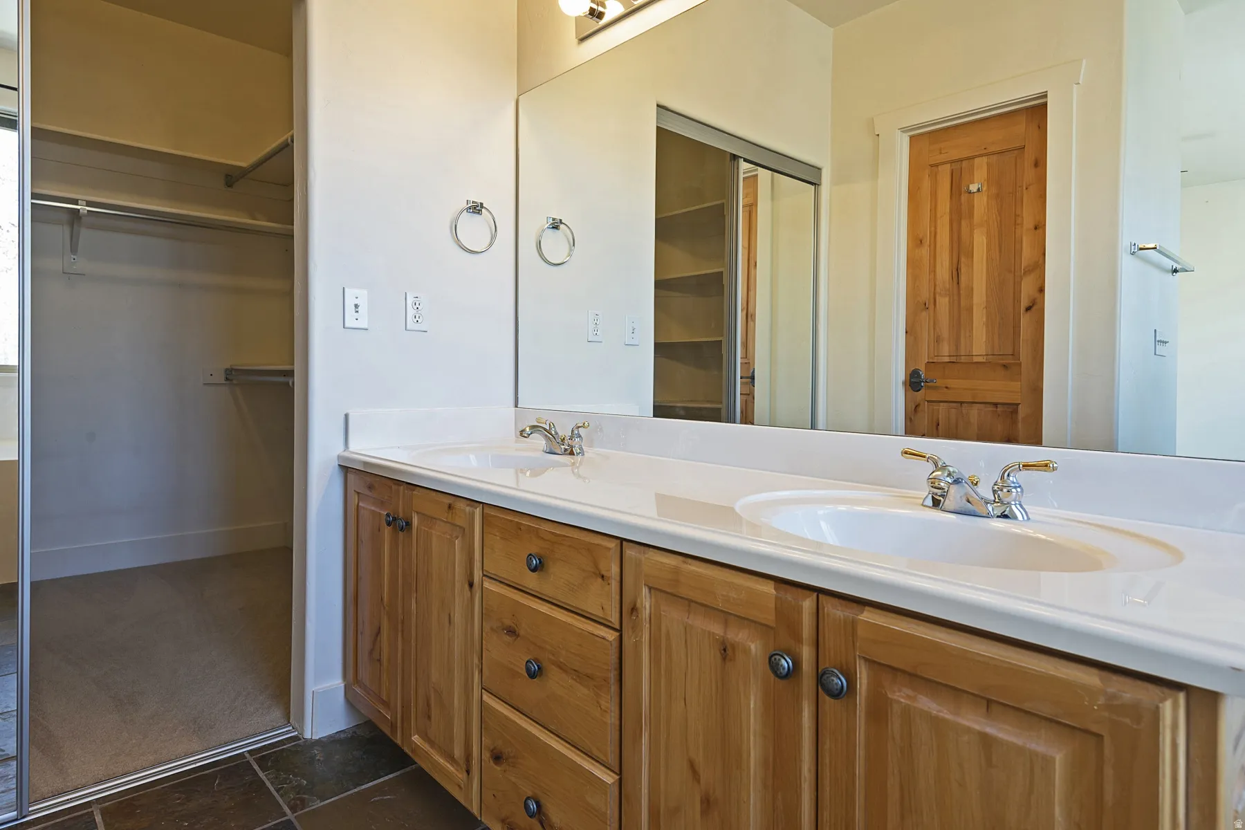 Dual vanity with undermount sinks, wood cabinetry, and a full-width mirror