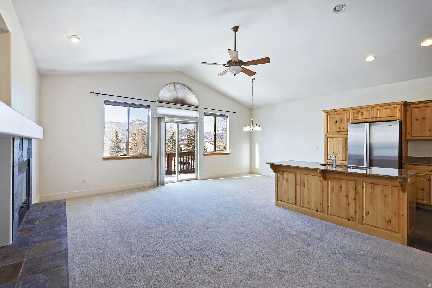 Vaulted ceilings, a built-in fireplace with a stone hearth, and extensive cabinetry with a kitchen island