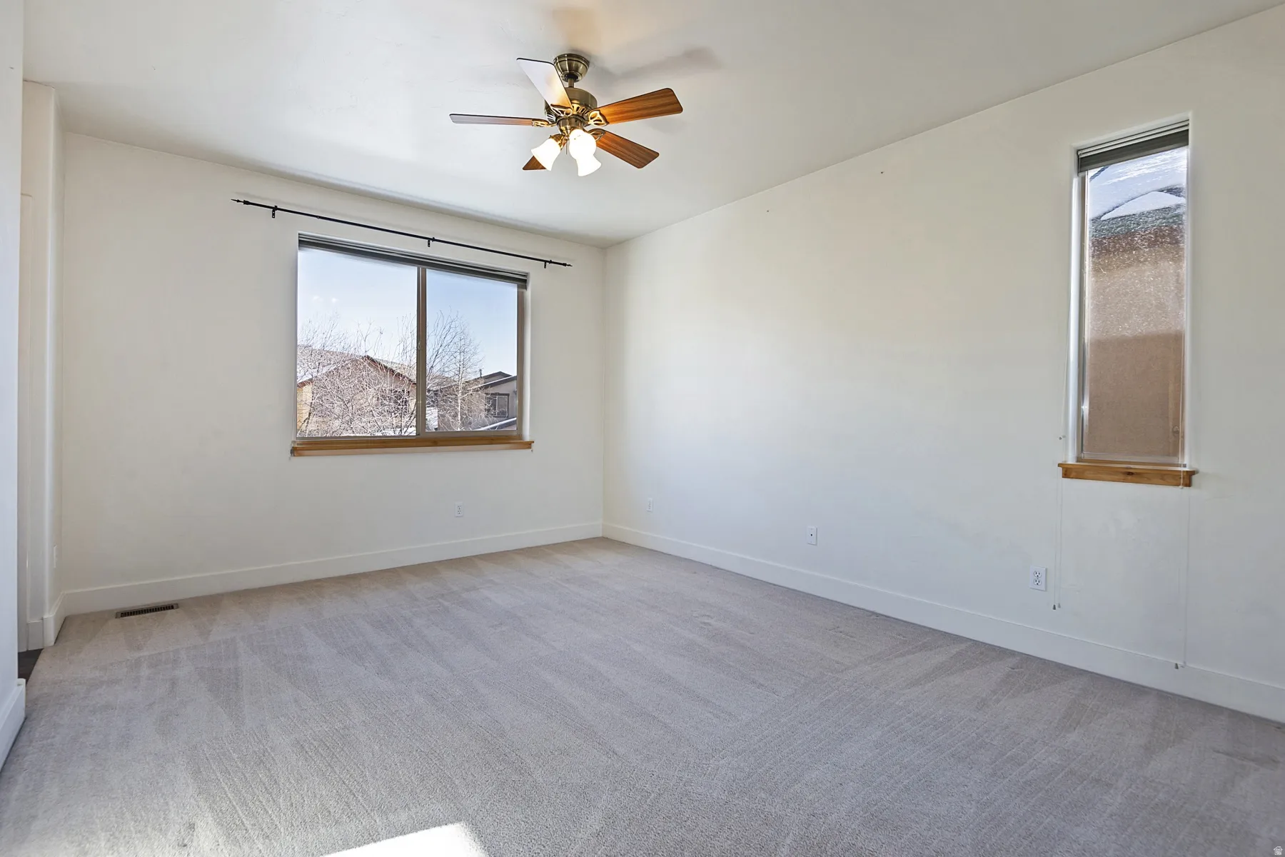 Neutral wall tones, light-toned carpeting, a ceiling fan, and multiple windows