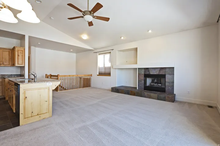 Vaulted ceiling with a ceiling fan, recessed lighting, and a stone-clad fireplace