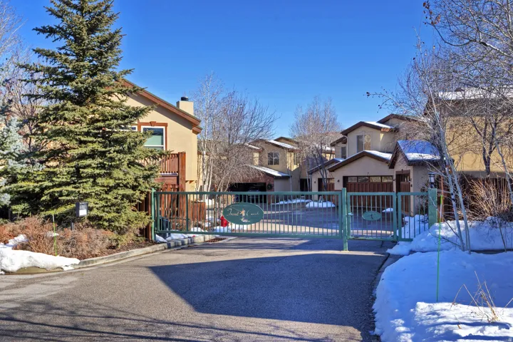 Gated community entrance with stucco exterior residences and attached garages