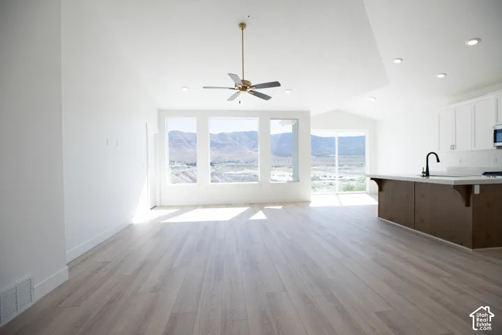 Great room with vaulted ceiling, ceiling fan and picture windows.